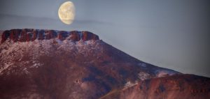 Moon appearing over mountain at dusk